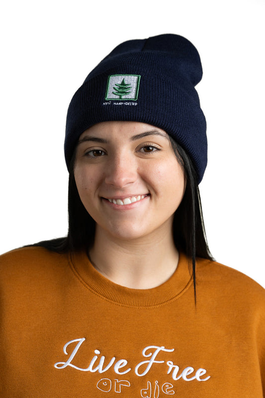 Model wearing navy blue New Hampshire embroidered cuff beanie featuring tree-inspired design