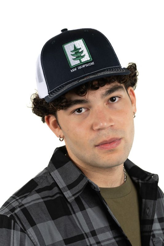 Model wearing New Hampshire embroidered trucker hat with premium leather patch and classic look