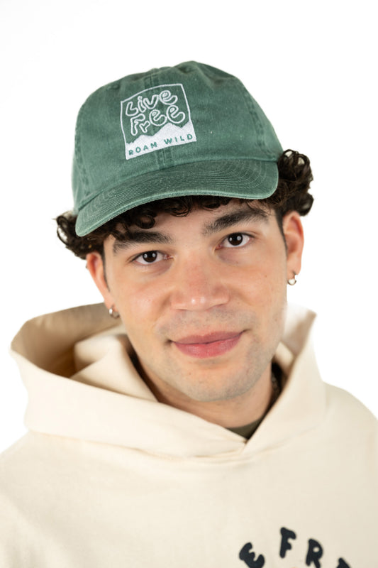 Model wearing deep green New Hampshire Roam Wild embroidered hat featuring bold graphic design