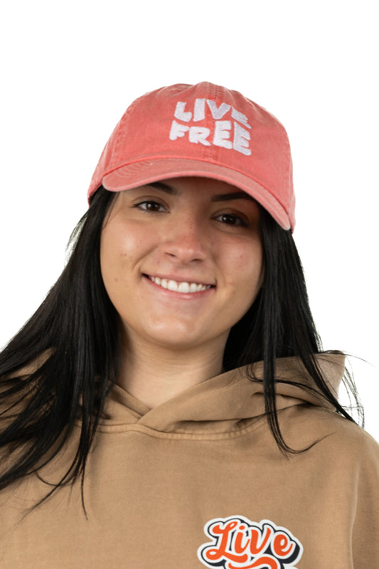 Model wearing coral unisex embroidered hat Live Free with stylish design and NH-inspired spirit